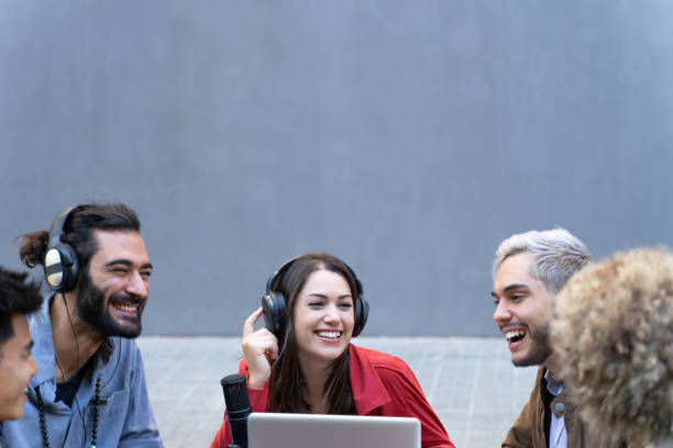 istock Group of young happy professionals around a computer chatting while working. Team of coworkers broadcasting a podcast interview. 2101805973