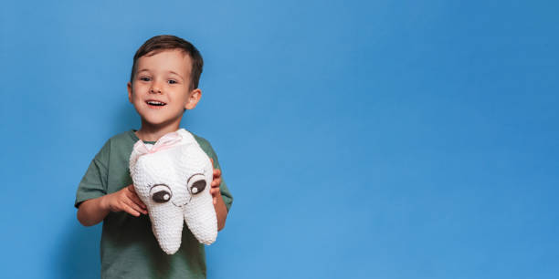 istock A smiling boy with a plush tooth on a blue background. Pediatric dentistry. A place for your text. Panoramic photo. 2101823635