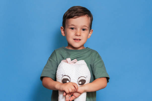 istock A smiling boy with healthy teeth holds a plush tooth on a blue background. Oral hygiene. Pediatric dentistry. 2101823672
