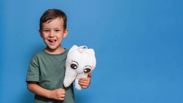 istock A smiling boy with healthy teeth holds a toothbrush and a plush tooth on a blue background. Pediatric dentistry. A place for your text. Panoramic photo. 2101824722