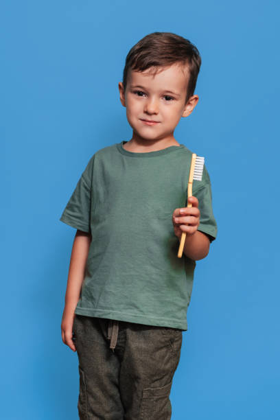 istock A smiling boy with healthy teeth holds a plus tooth and a toothbrush on a blue isolated background. Oral hygiene. Pediatric dentistry. Prevention of caries. vertical snapshot 2101824734