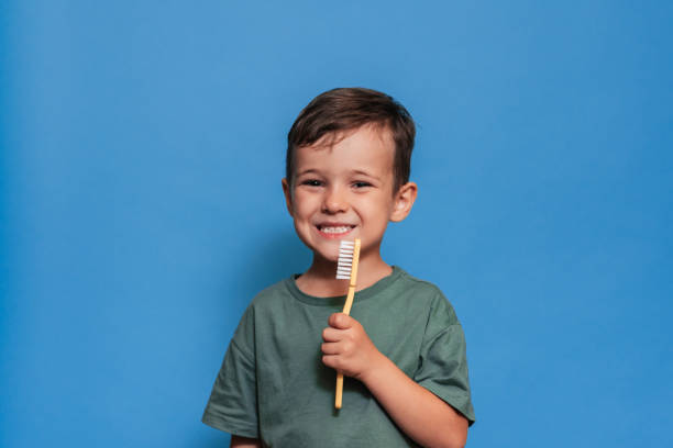 istock A smiling boy with healthy teeth holds a plus tooth and a toothbrush on a blue isolated background. Oral hygiene. Pediatric dentistry. Prevention of caries. 2101825244