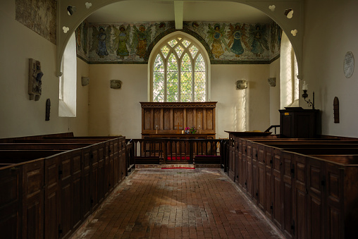 The interior of St Marys Church in East Guldeford, with altar, box pews and wall paintings.