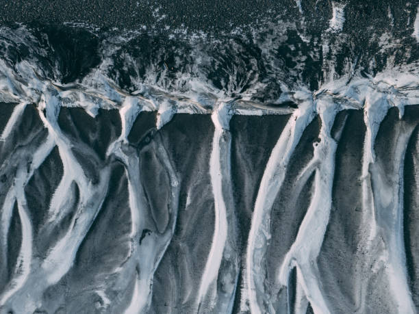 istock Ice flows heading into ocean through a volcanic black sand beach in Iceland. 2101887783