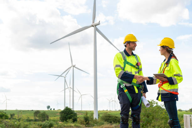 istock Smart engineers with protective helmet shaking hands at electrical turbines field 2101900038
