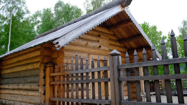 Old wooden house, cottage, Wooden palisade made of logs. Log wooden fence. Long sharp stakes