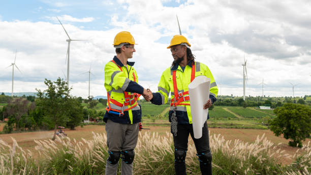 istock Smart engineers with protective helmet shaking hands at electrical turbines field 2101901083