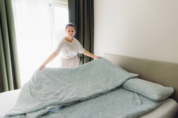 istock Woman Making Up Bed in Modern Bedroom 2101907660
