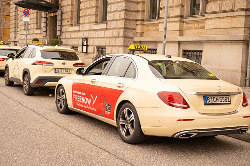 yellow Mercedes-Benz taxi with taxi company logos car on street of Frankfurt, brand automobile manufacturer, innovation automotive industry, Berlin, Germany - February 18, 2024
