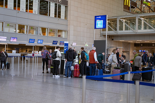 Airport terminal, passengers with luggage stand in line to check in for flight, vacation is evident in faces of passengers wait to board their flight, Frankfurt, Germany - March 2, 2024