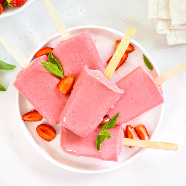 istock Strawberry ice cream popsicles on white plate 2101943668