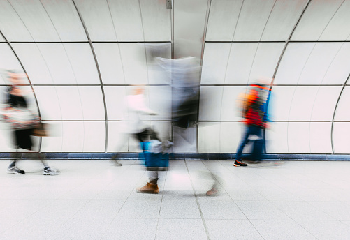 Long exposure image depicting blurred motion of busy commuters on the London underground.