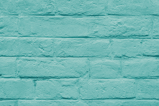 Abstract weathered masonry, aged texture. Stained old stucco turquoise painted  brick wall background, grungy rusty blocks of brickwork close up. Wallpaper, backdrop