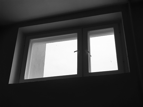 An old wooden black and white window in a dark room.