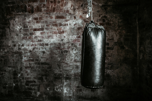 Punching bag against old brick wall background