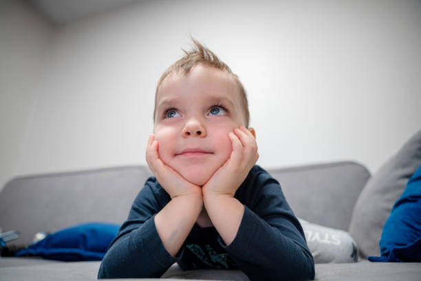 Cute little boy laying on the sofa and watching tv
