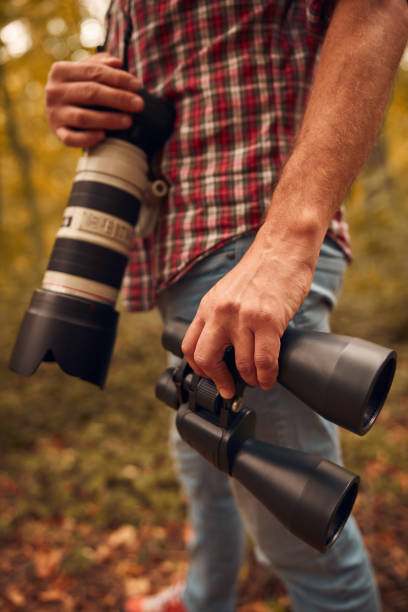 istock Man using binoculars and camera for birdwatching and other observing animals in nature. 2102017858