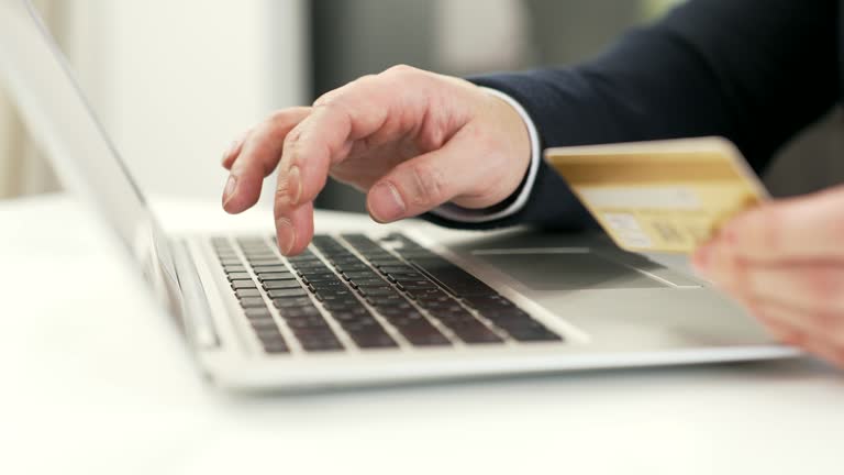 Close up of male hands holding a credit card and typing on a laptop