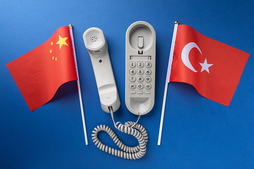 Flag of China, Turkey and old corded telephone on a blue background, concept on the theme of telephone conversations between countries