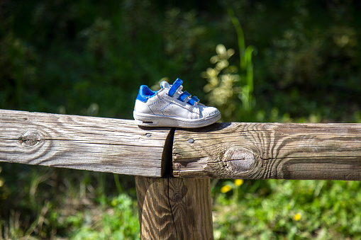 one lost child's white shoe on a wooden fence in the park