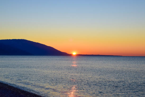 istock The sun rises from behind the mountains. Dawn over the sea. 2102052992