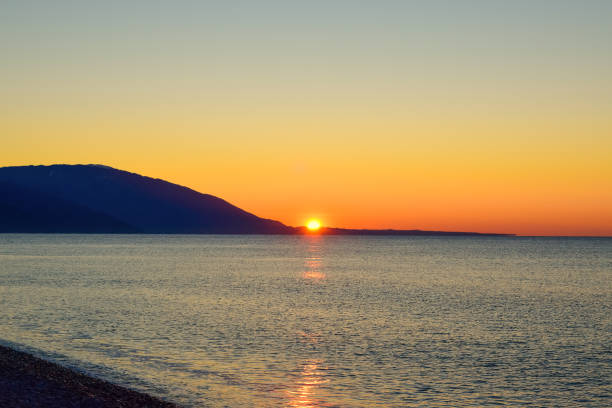 istock The sun rises from behind the mountains. Dawn over the sea. 2102054056