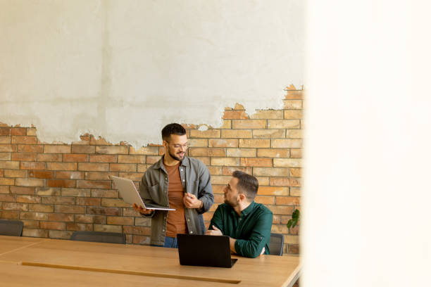 istock Collaboration in Motion, Professionals Working Together in a Modern Brick-Walled Office 2102083231