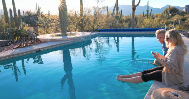 Mature couple relax at desert swimming pool at dawn