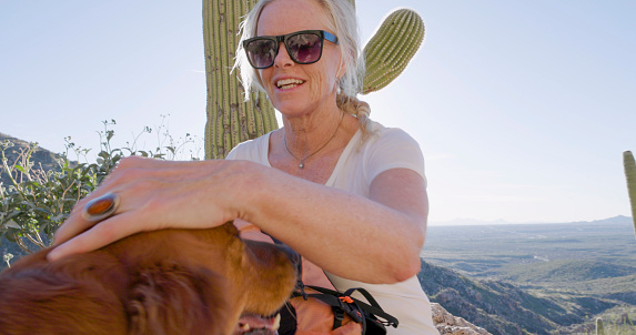 Mature woman hiker pauses in desert with dog