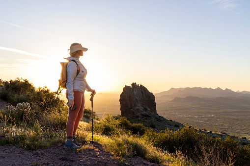Mature woman hiker watches sunset over desert landscape