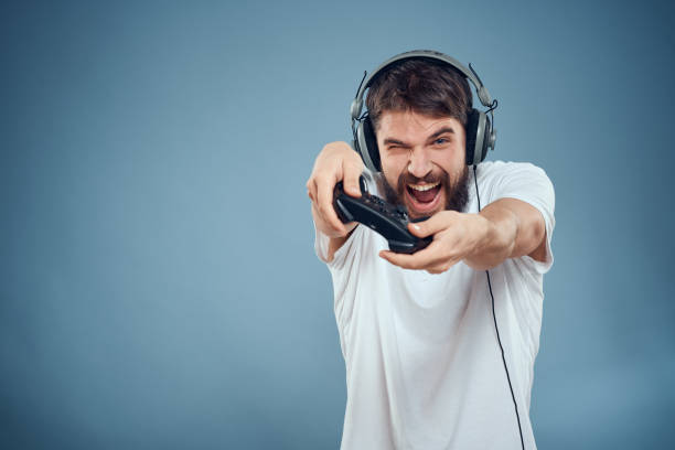 istock Man in headphones controller in hands playing game console lifestyle emotions blue background white t-shirt 2102111310