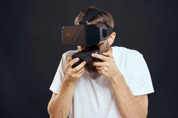 istock man wearing virtual reality glasses with gamepad in hand technology games leisure dark background 2102112345