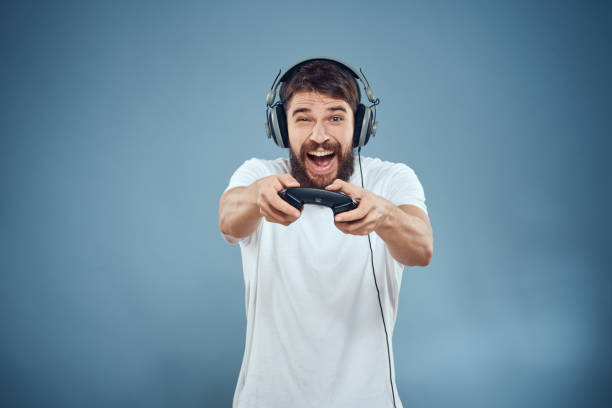 istock Man in headphones controller in hands playing game console lifestyle emotions blue background white t-shirt 2102113356