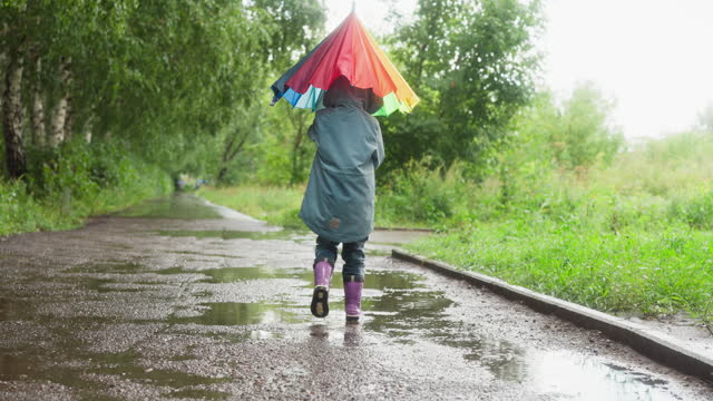 Child closes umbrella walking in park