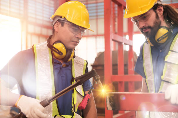A group of dedicated workers in a metal workshop, skillfully welding a metal structure to perfection.
