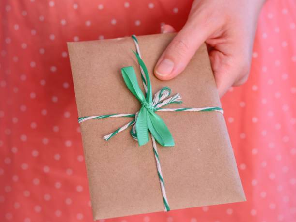 istock A woman giving a small present with a green bow. 2102120261