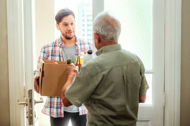 Young Man Delivering Groceries to Elderly Homeowner