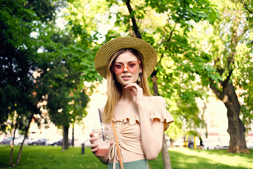 beautiful woman walks in the park outdoors with a drink Lifestyle. High quality photo