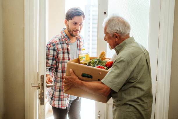 istock Young Man Delivering Groceries to Elderly Neighbor 2102164413