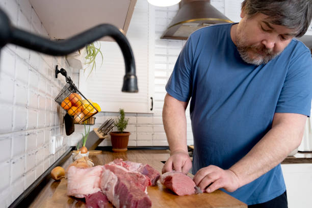 istock Real men cutting fresh raw meat on  board in white kitchen. Preparing pork meat, cooking 2102168054