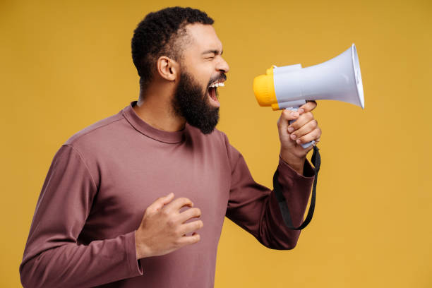 istock Pensive, angry African American man holding megaphone, shouting, announcing with closed eyes 2102173810