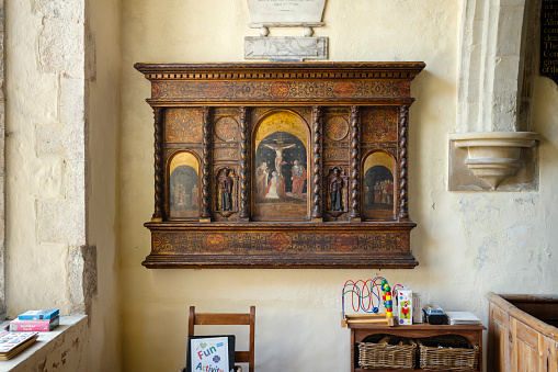 Interior showing a painted and gilded panel showing the crucifixion of Christ, with children toys all around.