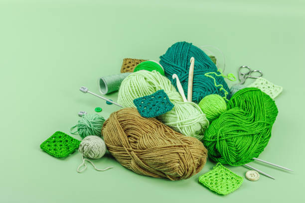 A set of knitting yarn and tools in spring colors. Handmade concept, creative art, crafting process. Hobby, relax, lifestyle, flat lay on pastel green background, copy space