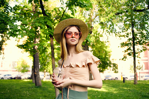 pretty woman in a hat in the park drink rest greens. High quality photo