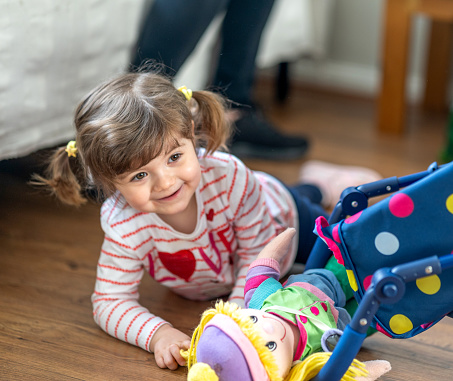 Two year old girl lifestyle portrait playing with dolls