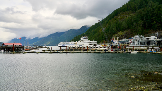Horseshoe Bay, Canada – February 26, 2024: Two BC Ferries leaving the Horseshoe Bay Fery terminal, with scenic majestic mountains in the background