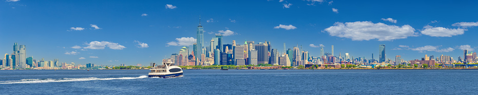 New York City Skyline with Jersey City, NJ with Goldman Sachs Tower, Battery Park, World Trade Center, Manhattan Financial District, Empire State Building, Chrysler Building, NYC Ferry Boat, Governors Island, Red Hook neighborhood of Brooklyn, Blue Sky with Puffy Clouds and Water of New York Harbor. High Resolution Stitched Panoramic image with 5:1 image aspect ratio. This image was downsized to 50MP. Original image resolution is 79MP or 19,885 x 3,977px. Canon EOS 6D Full Frame Sensor Camera and Canon EF 70-200mm f/4L IS USM Lens.
