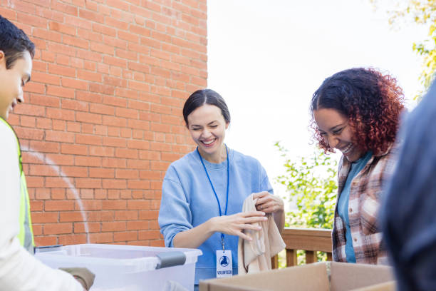 istock Diverse group of volunteers work together to fold clothing items 2102214052
