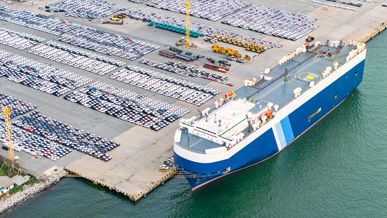 Aerial view Ro-Ro Ship of business logistic sea freight, New Cars produced by year up in the port for Cargo ship and Cargo import-export around in the world. cargo ship by tug boat