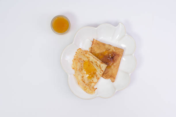 Thin pancakes with appricot jam on white background, top view. High quality photo